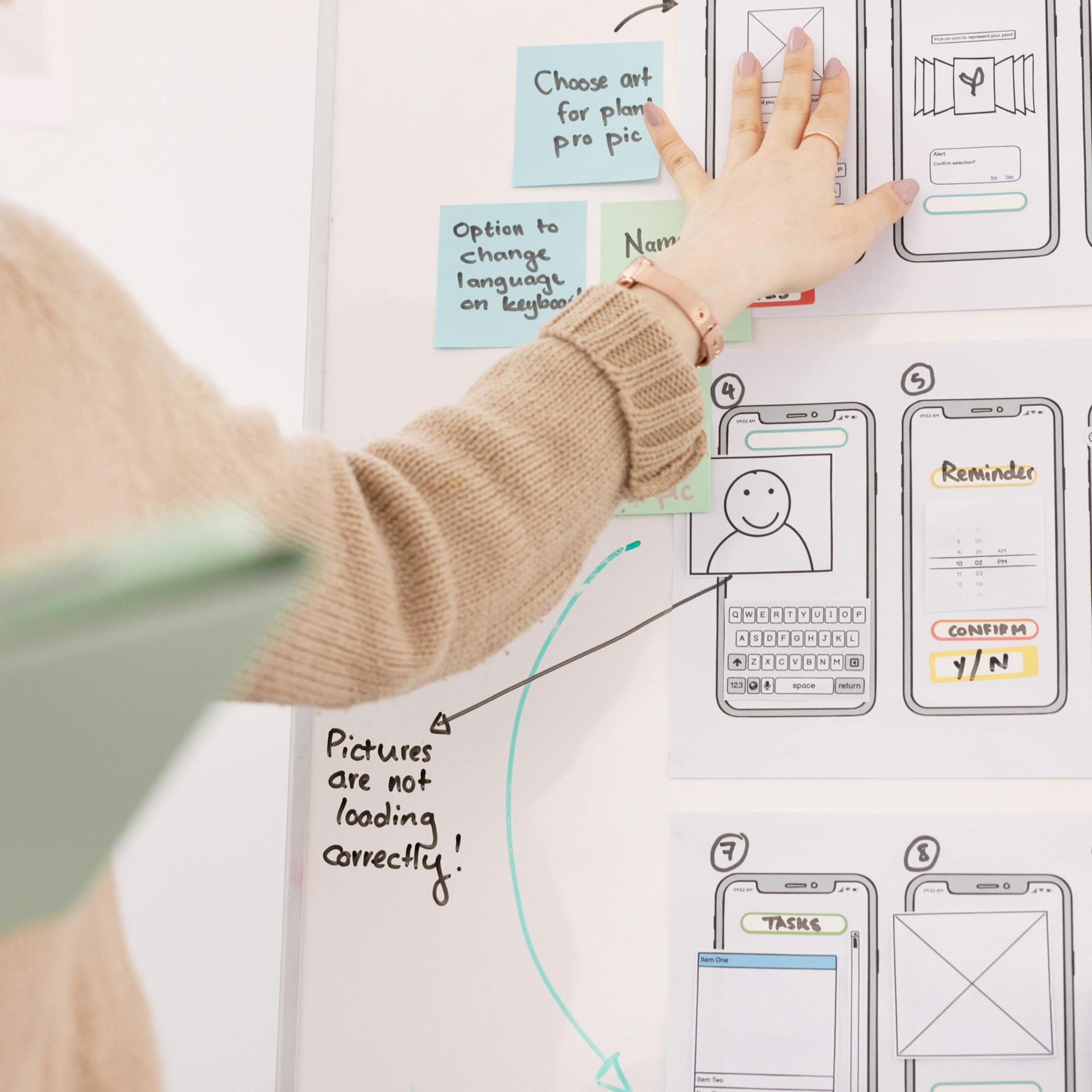 A person gesturing to wireframes pinned up on a board