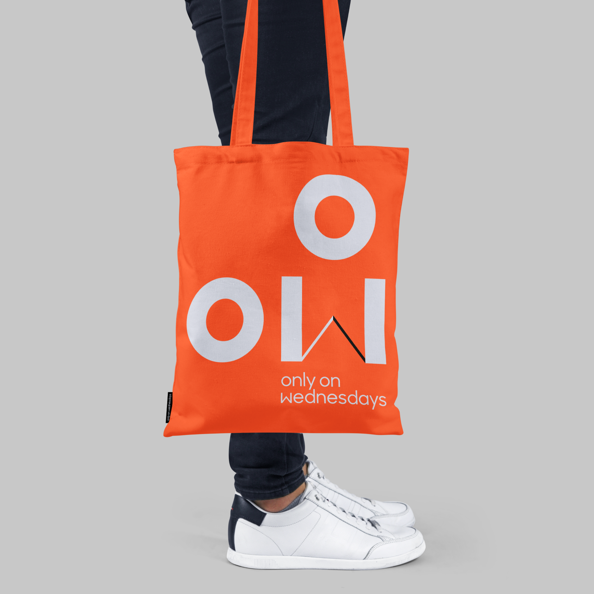 Only on Wednesdays branded orange tote bag being carried at a person's side