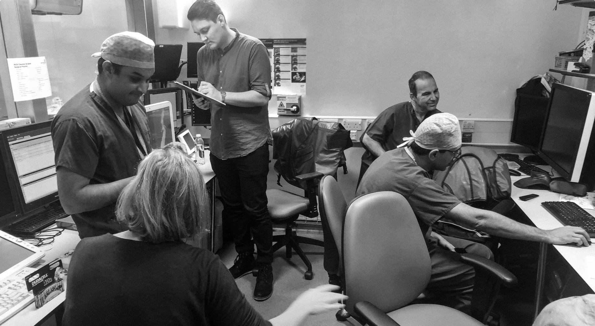 A black-and-white photo of several medical professionals working together in an office setting.