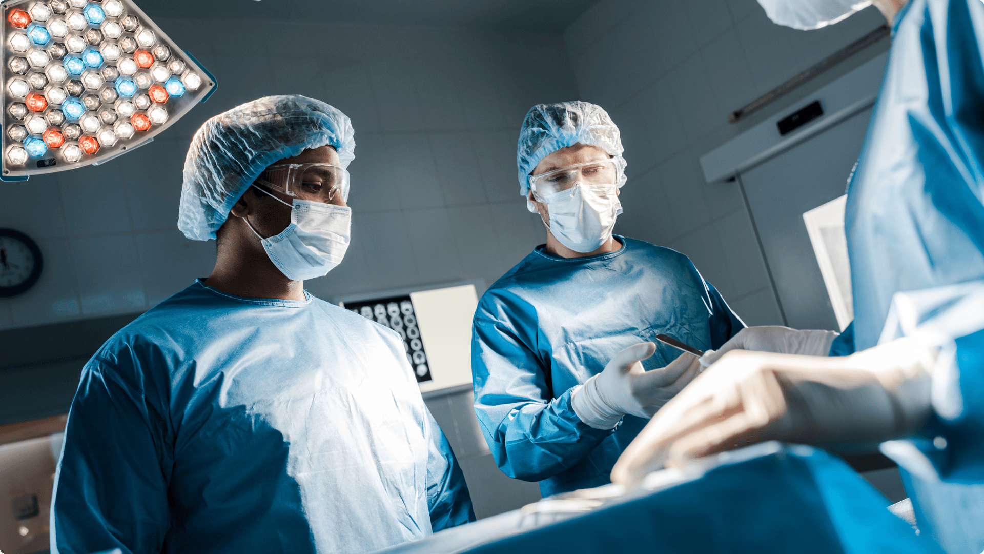 Three surgeons in full scrubs and surgical masks in an operating theatre carrying out an operation Three surgeons in full scrubs and surgical masks in an operating theatre carrying out an operation