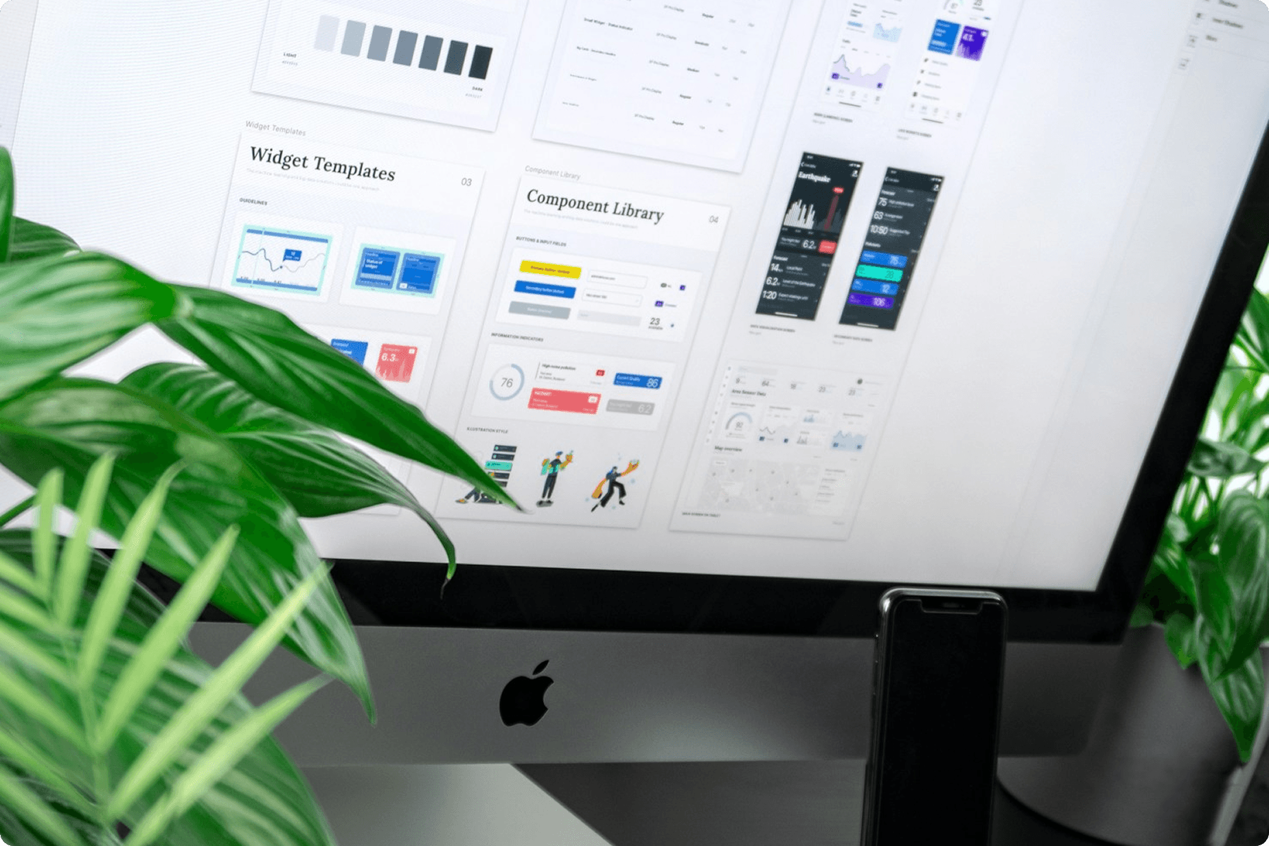 A computer on a table with lots of plants in the foreground. The screen shows a CMS for a website. A computer on a table with lots of plants in the foreground. The screen shows a CMS for a website.
