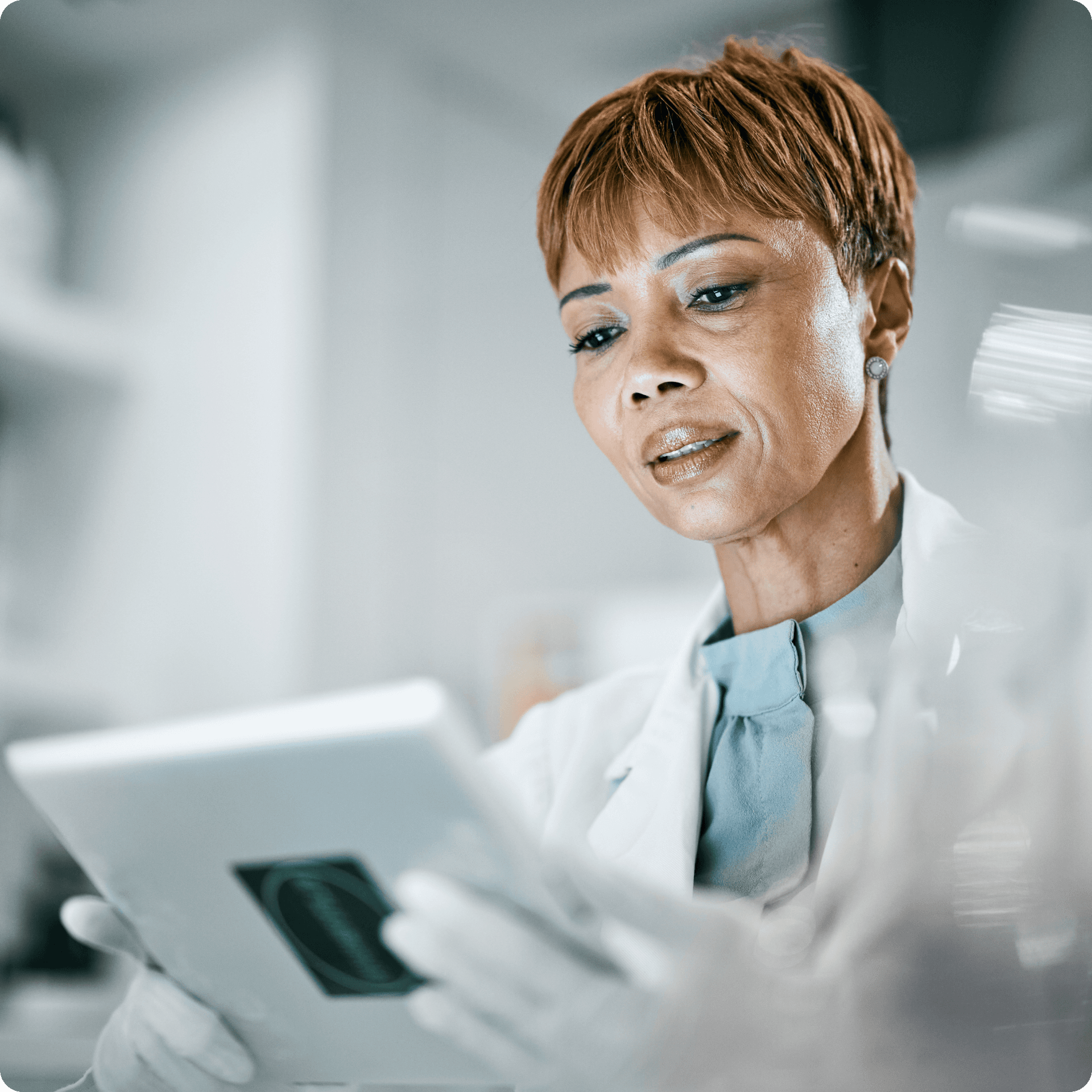 A medical professional is shown looking at a tablet screen, her expression is impartial. A medical professional is shown looking at a tablet screen, her expression is impartial.