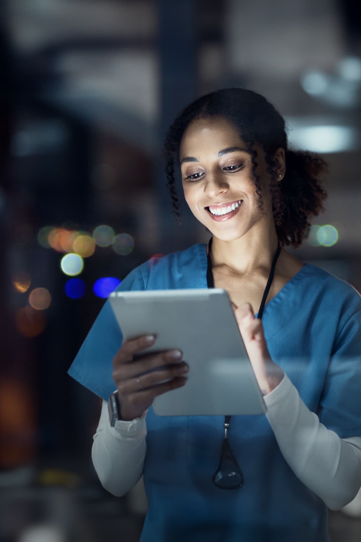 Image of a nurse at working at night using a tablet. the light is illuminating her face Image of a nurse at working at night using a tablet. the light is illuminating her face