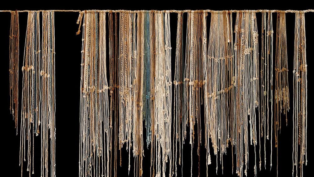 Several brown talking knots, known as quipa, that are hanging in a row. Several brown talking knots, known as quipa, that are hanging in a row.