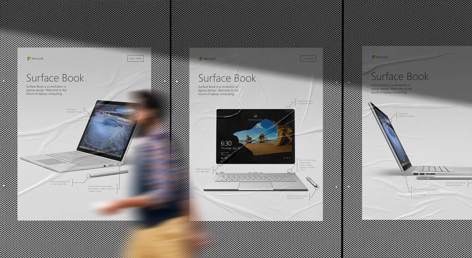 3 posters for "Surface Book" appear on a wall. A blurred image of a man can be seen walking past. 3 posters for "Surface Book" appear on a wall. A blurred image of a man can be seen walking past.