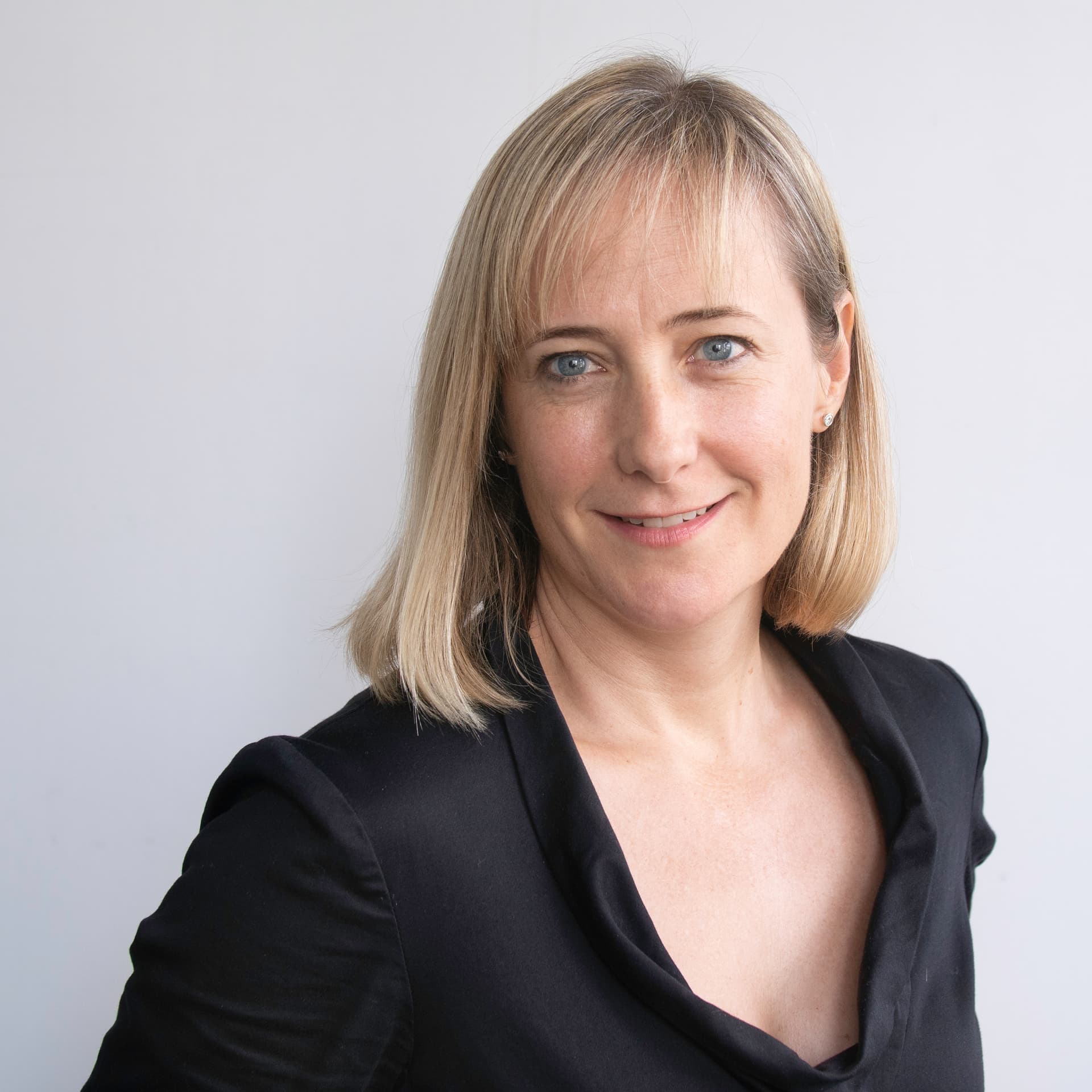 Leslie has blonde hair and smiles at the camera. She is wearing a black top. Leslie has blonde hair and smiles at the camera. She is wearing a black top.