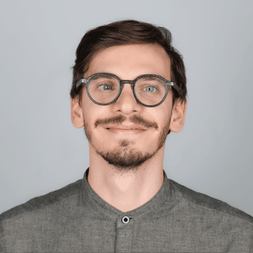Alessandro smiles at the camera. He is wearing a grey shirt.  Alessandro smiles at the camera. He is wearing a grey shirt.